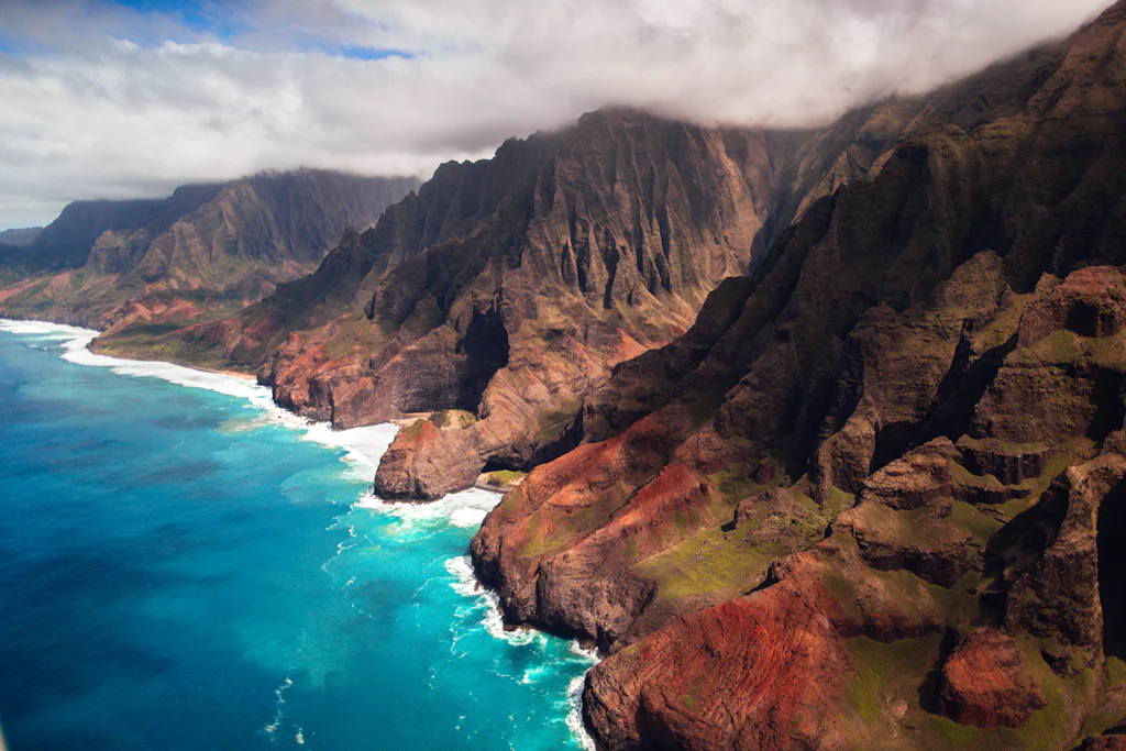 Aerial view of the fluted green cliffs of the Na Pali Coast, the heart of the best hikes in Kauai