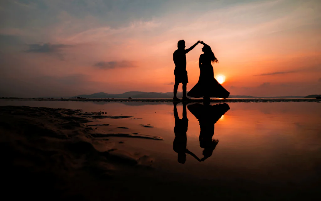 Couple walking barefoot along a Hawaiian beach at sunset on their honeymoon