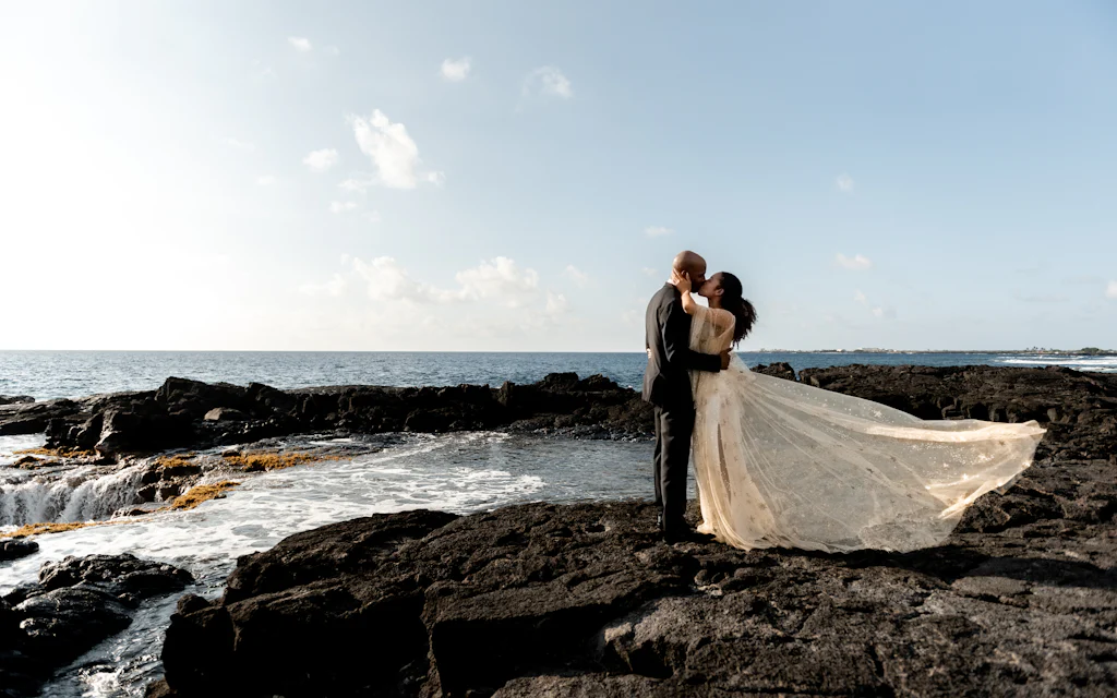 Newlywed couple embracing by the ocean at a Hawaii beach wedding