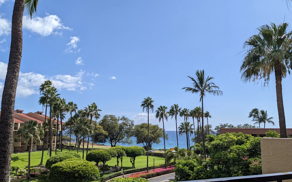 Kamaole Sands Maui condo buildings and garden courtyard from a lanai in Kihei with the ocean beyond
