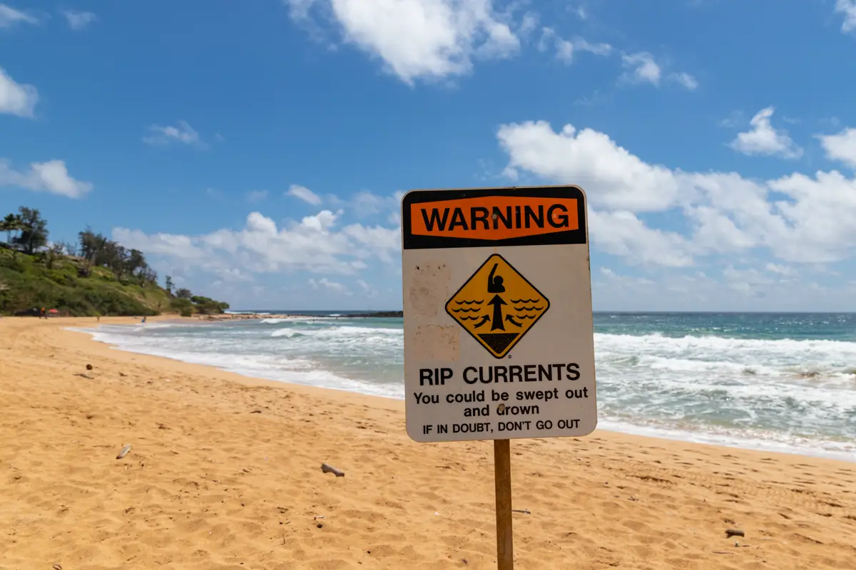 Rip current warning sign on the sand at Kealia Beach Kauai