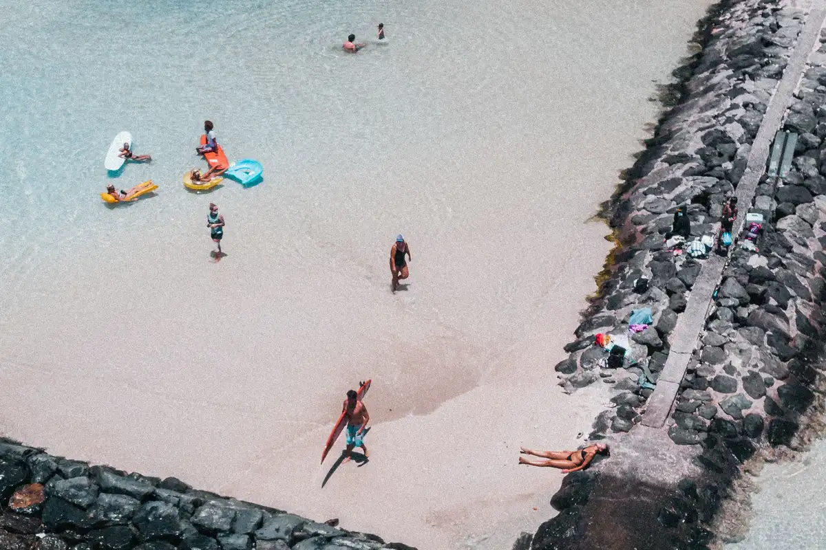 A calm Ko Olina lagoon on Oahu's sunny west side, ringed by a rock wall and white sand
