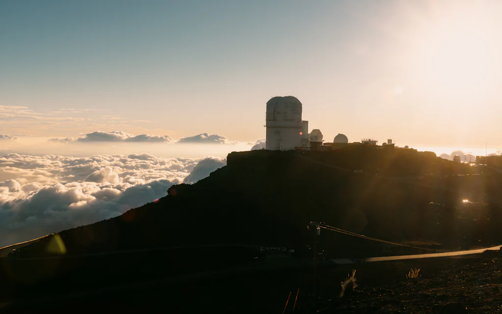 Observatories on a summit above the clouds at sunset, like Mauna Kea