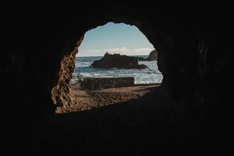 Light beaming through a sea cave opening onto ocean water, like the Mermaid Cave in Oahu
