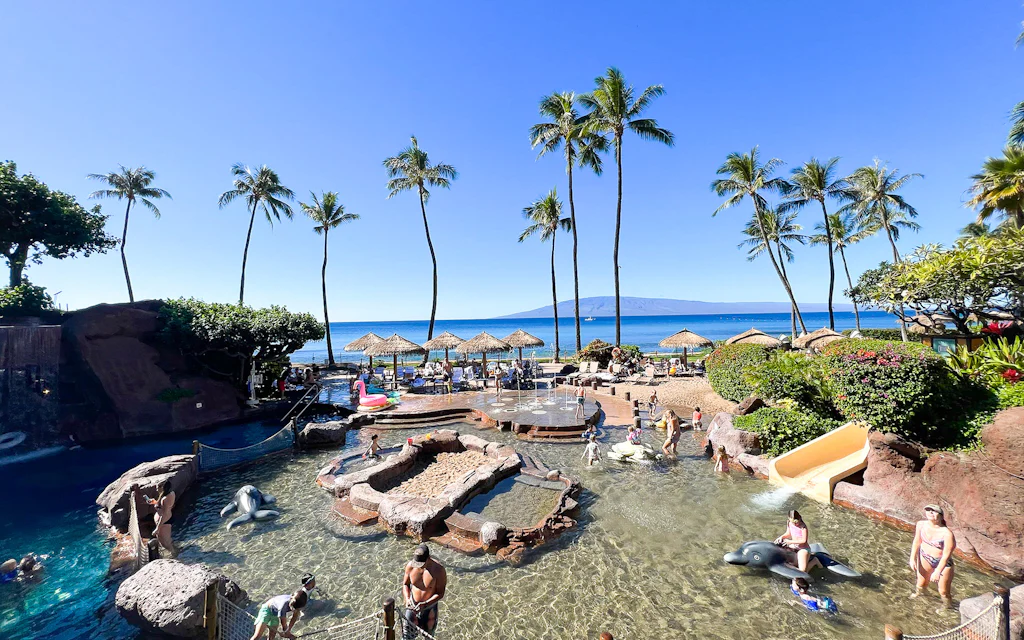 Families playing in the calm shallow water at an Oahu beach with kids