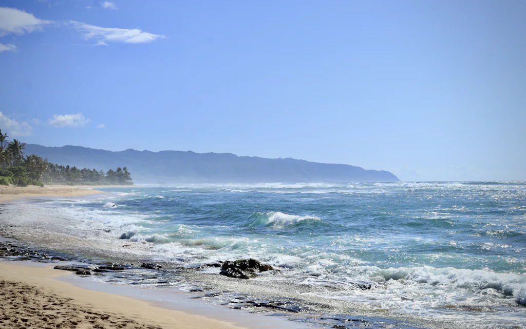 Waves rolling onto the quiet white sand of a North Shore Oahu beach near Papailoa Beach