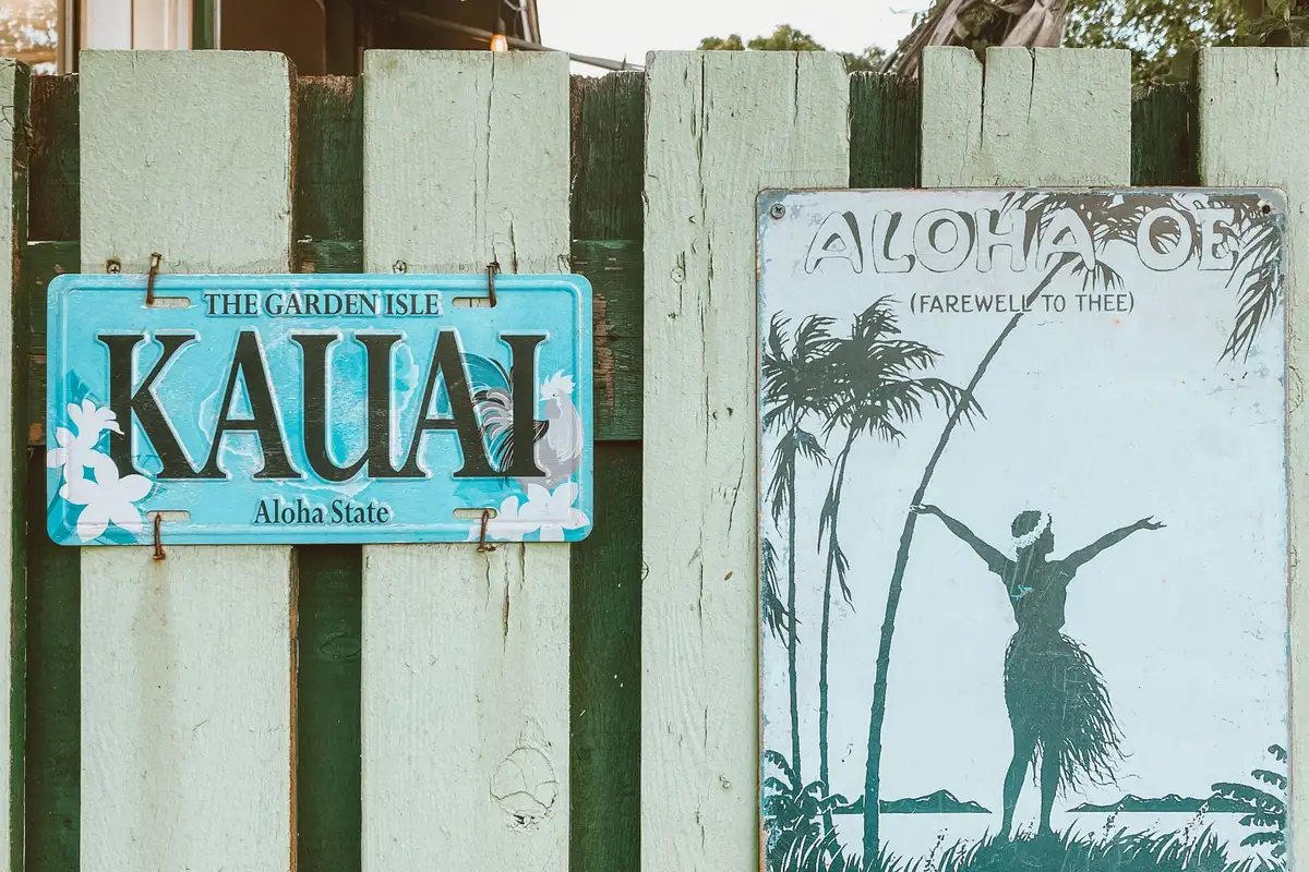 Vintage Kauai and Aloha Oe signs on a weathered fence in Old Koloa Town