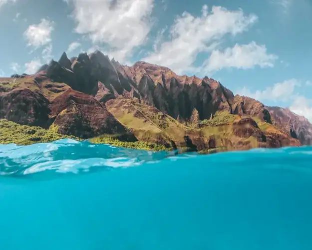 Bright blue ocean water meeting the rugged cliffs of Kauai's north shore near Queen's Bath