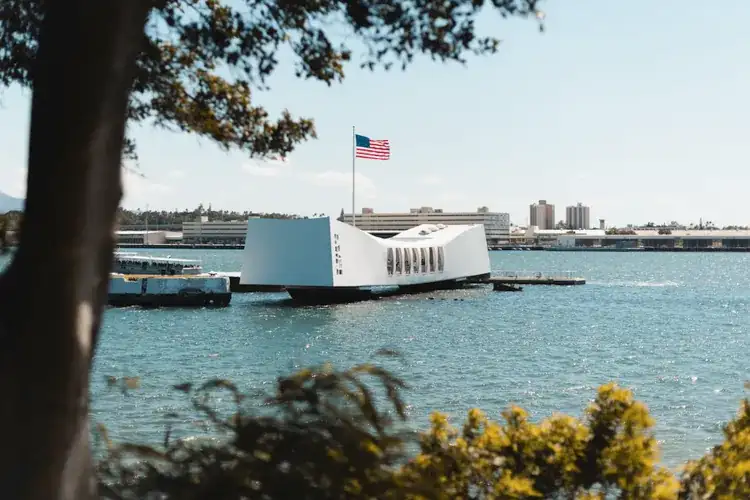 The white USS Arizona Memorial above the water at Pearl Harbor with the American flag flying