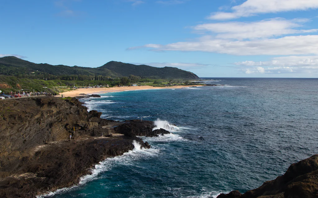 View over the bright blue water of Waimea Bay on Oahu's North Shore from the cliff above